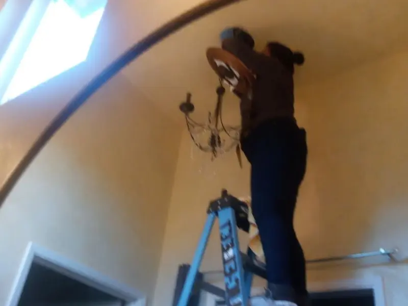 Electrician installing a chandelier in a Springville residence